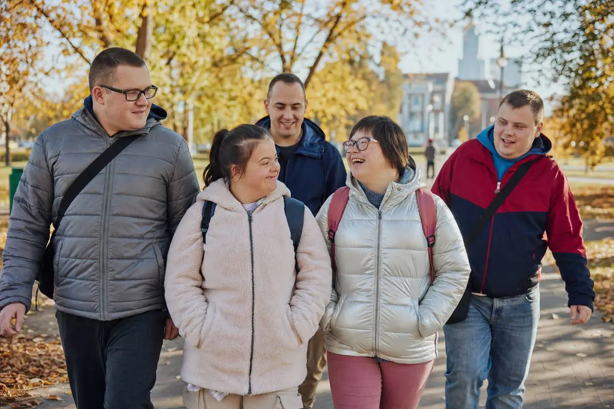 Grupa mieszkańców spaceruje razem w parku w słoneczny jesienny dzień